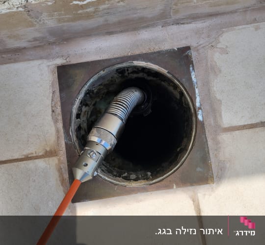 צינור מתכת נכנס לפתח ניקוז ברצפה